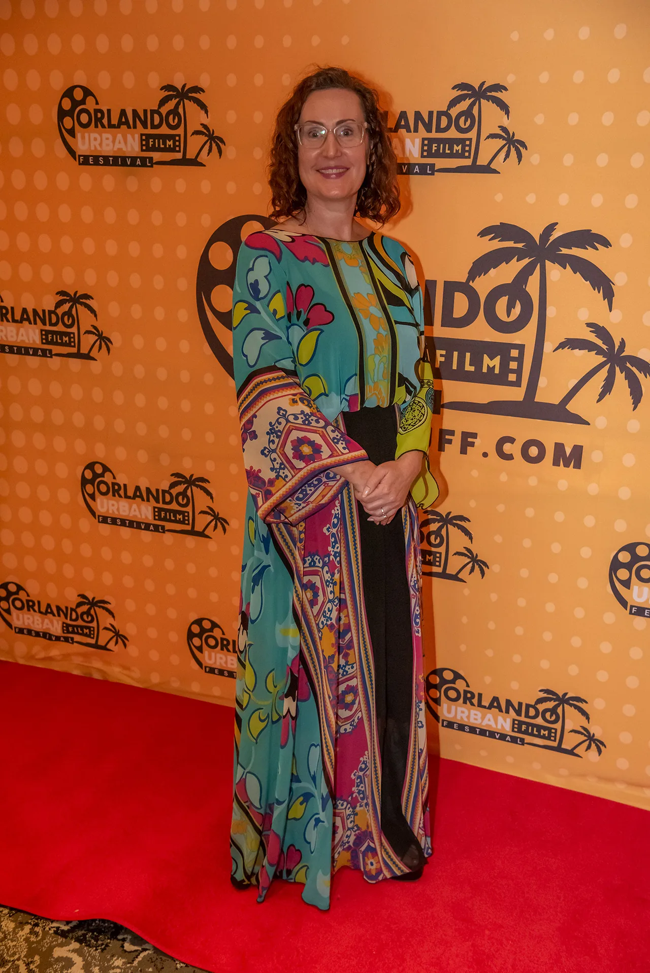 A filmmaker in a brightly patterned floor-length gown on the red carpet