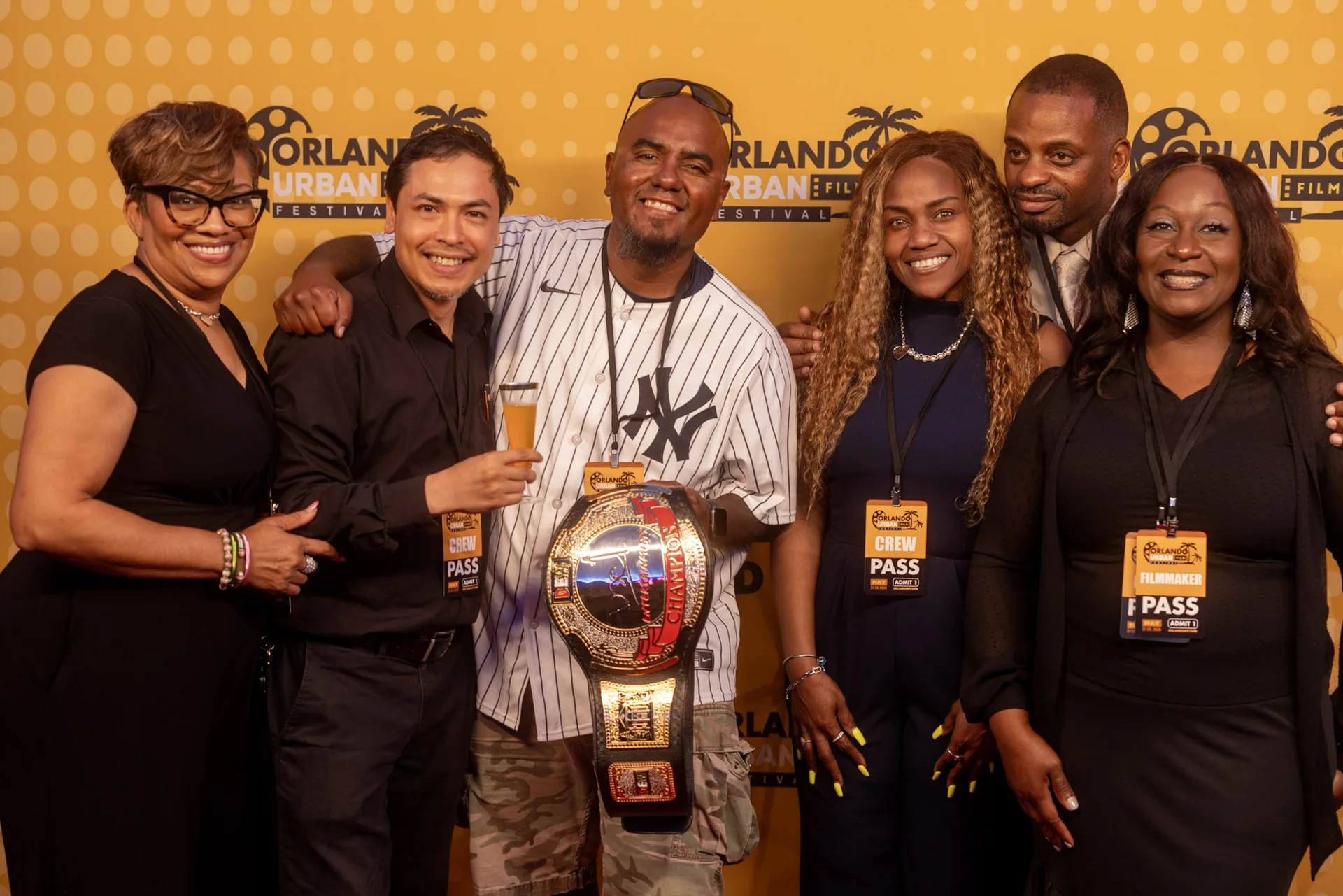 Festival guests crowded together on the red carpet, one holding a championship belt