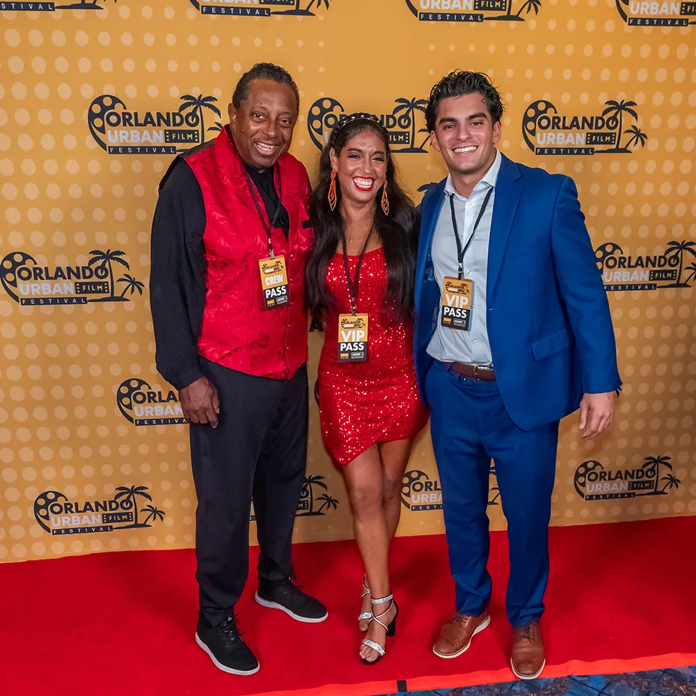 Three festival guests posing together on the red carpet in front of the step-and-repeat
