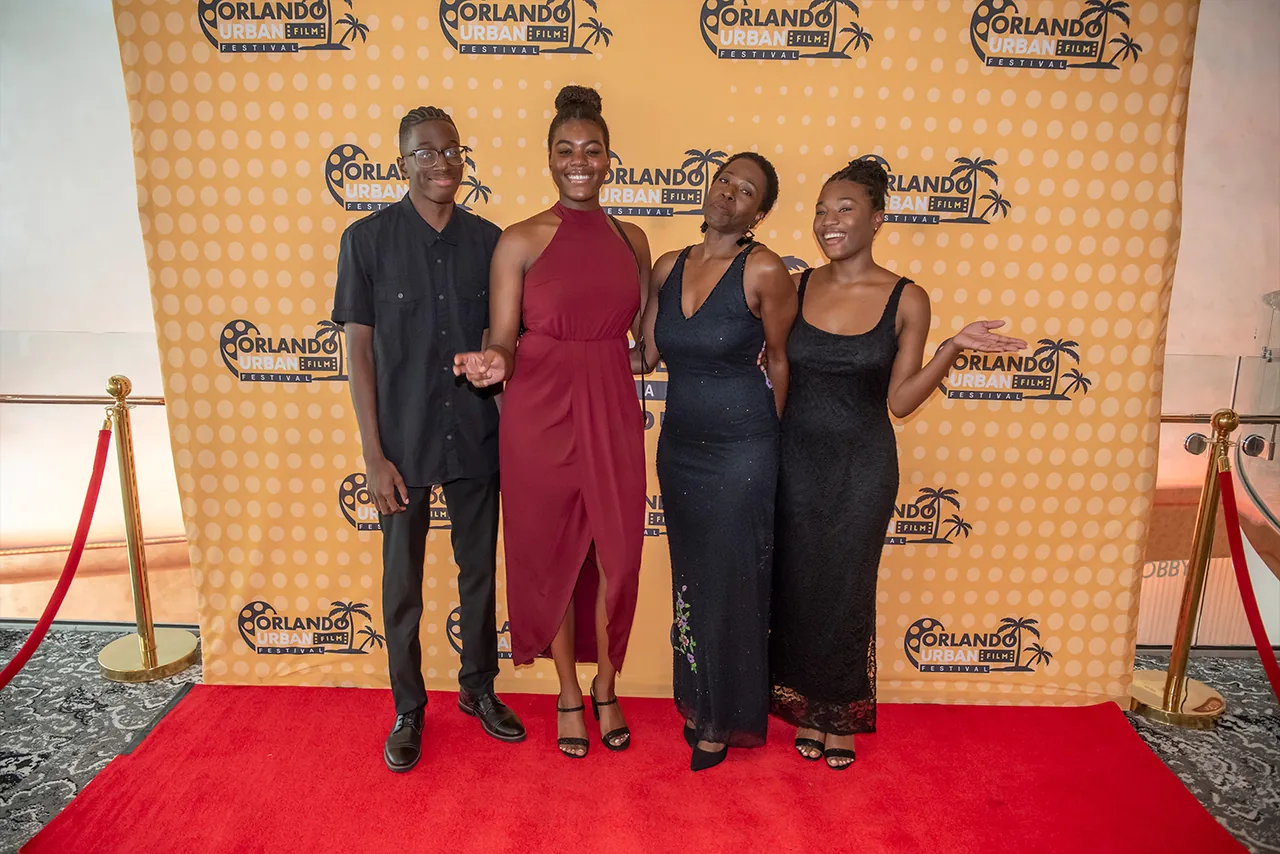 Four guests in evening wear standing together on the red carpet